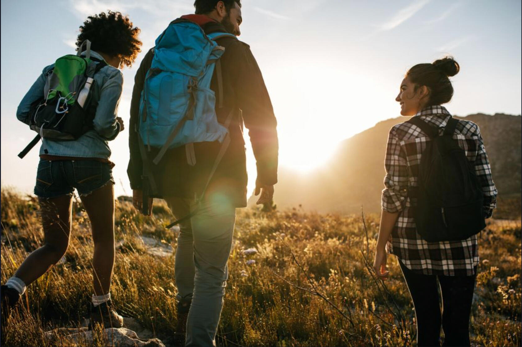 three diverse hikers walking into the sunrise